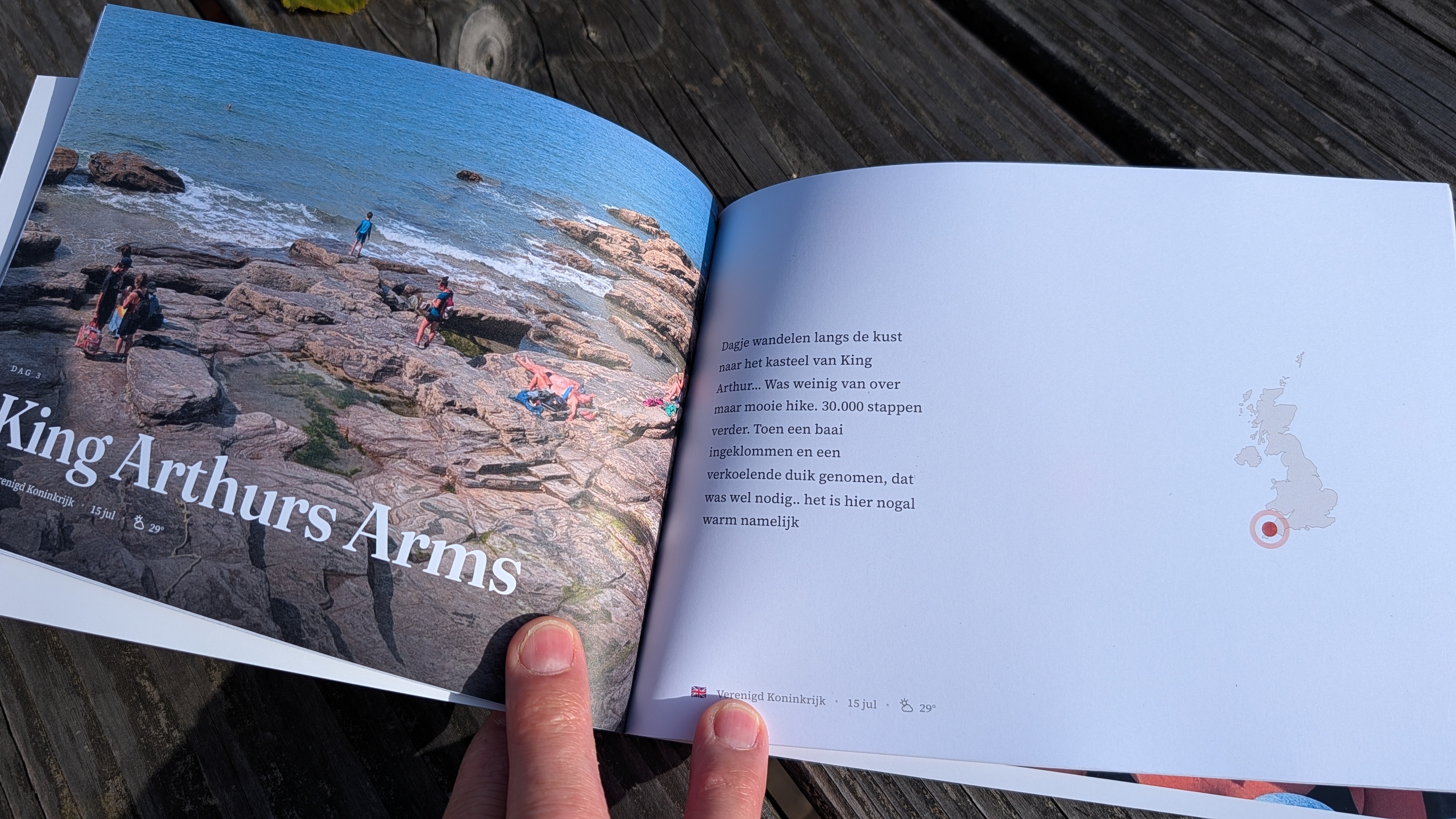 Een open vakantiefotoboek met foto's en een routepagina, vastgehouden op tafel