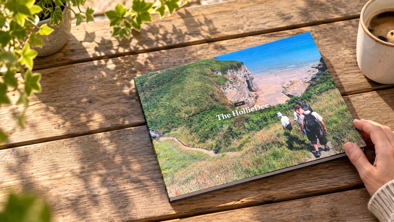 Een gedrukt vakantiefotoboek op een houten tafel, met een hand die het boek vasthoudt